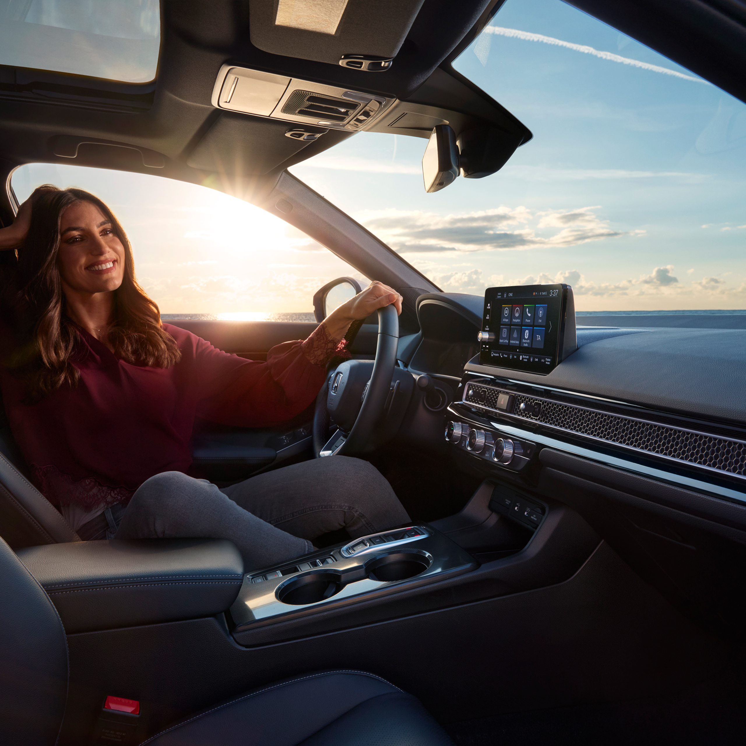 Photo shot from the interior of Civic Hybrid, a woman sitting in the car, next to the sea.